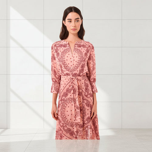 Woman wearing a pink patterned dress on a white background