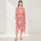 Woman wearing a pink patterned dress on a white background