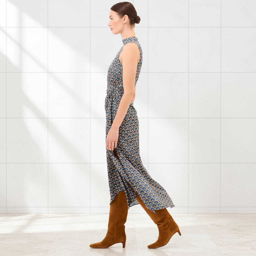 Woman wearing a patterned dress and brown boots on a white background