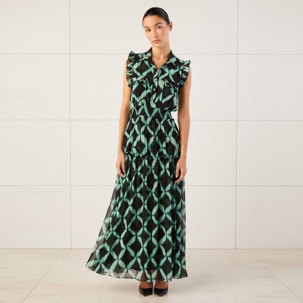 Woman wearing a green and black patterned dress with ruffled shoulders on a white background