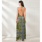 Woman wearing a green patterned dress with open back on a white background
